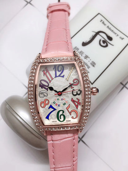 a pink watch sitting on top of a table next to a tube of cream