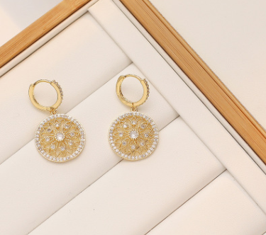 a pair of gold and diamond earrings sitting on top of a white box