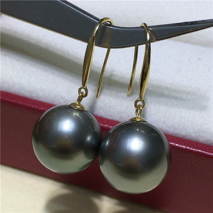 a pair of black pearls hang from a pair of gold - plated earrings