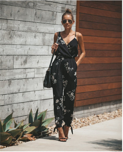 a woman wearing a black floral print jumpsuit