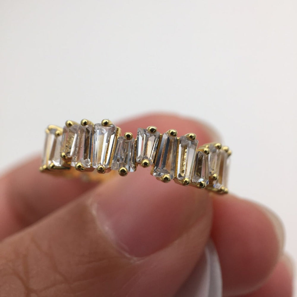 a person holding a gold ring with a baguette cut diamond