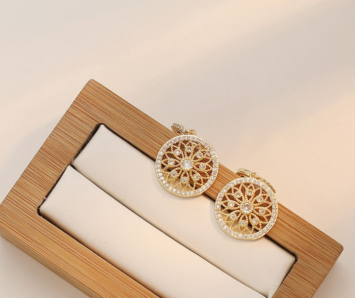 a pair of earrings sitting on top of a wooden box