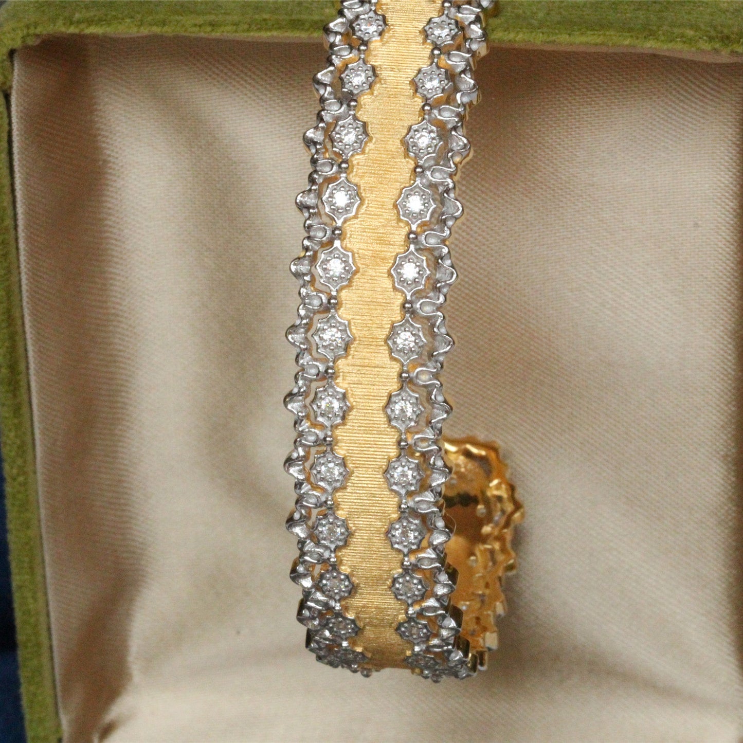 a gold and diamond bracelet in a green box