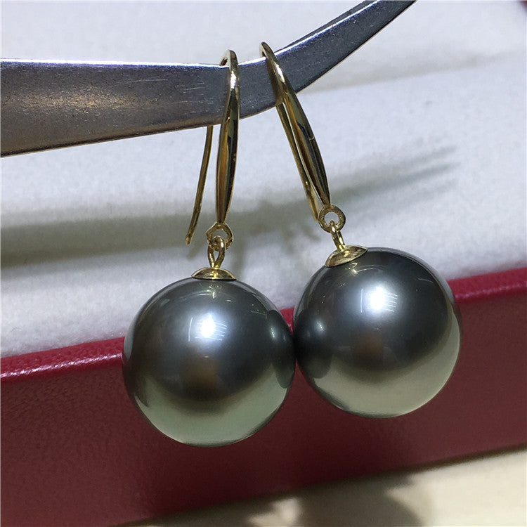 a pair of black and white pearls hanging from a pair of gold - plated
