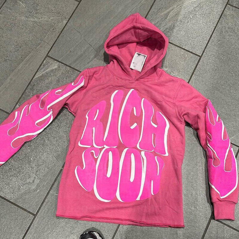 a pink hoodie with a pair of sneakers on the ground
