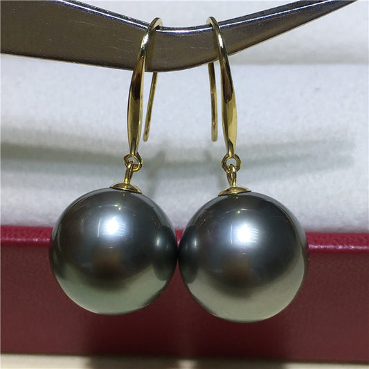 a pair of black pearls hang from a pair of gold earrings