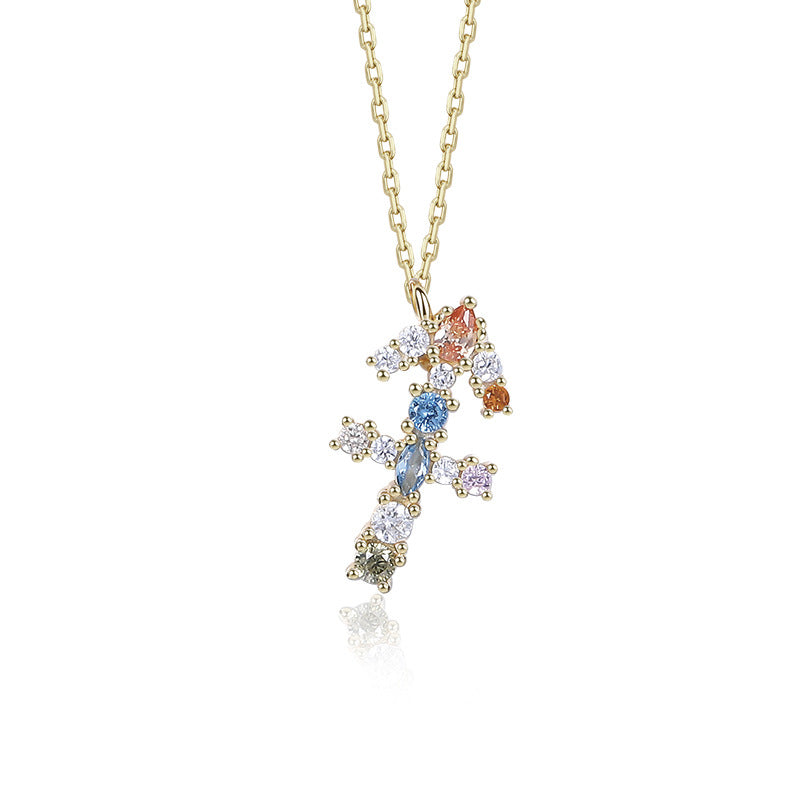 a cross necklace with multicolored stones on a gold chain