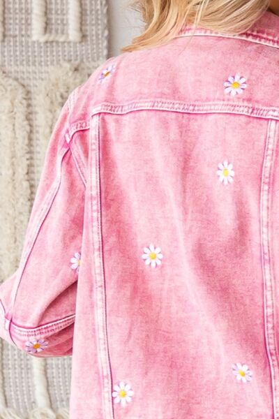 a woman wearing a pink jean jacket with daisies on it